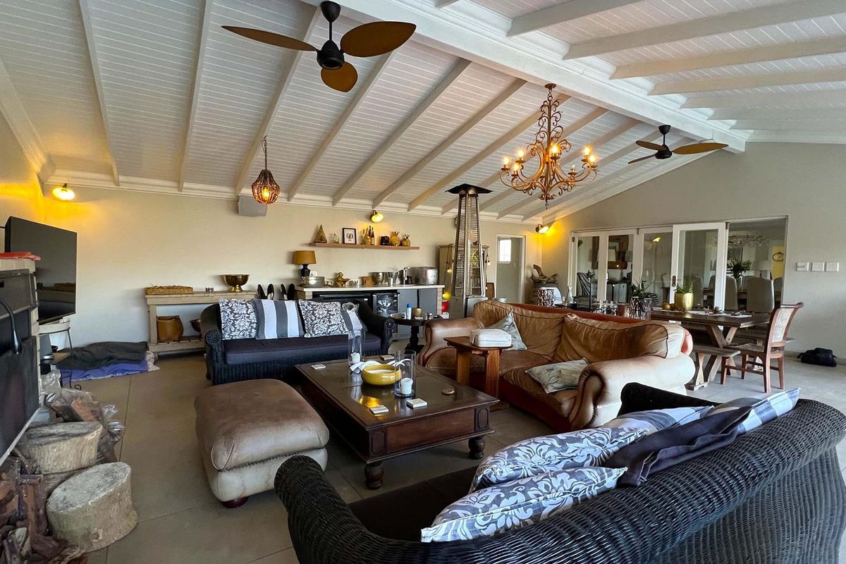 Spacious living area featuring a high exposed beam ceiling, ceiling fans, and a built-in fireplace, creating a comfortable and inviting atmosphere.