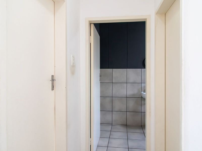 A clean hallway providing access to adjacent rooms, featuring neutral wall finishes and tiled flooring.