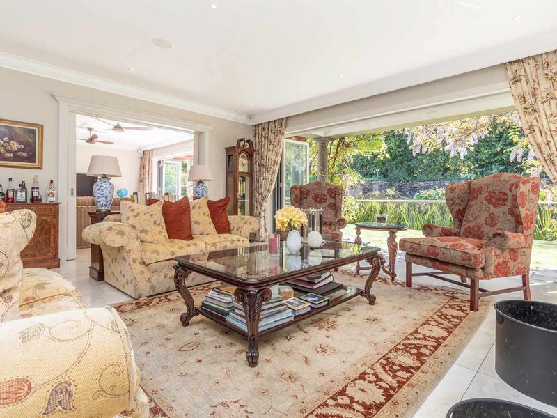 Spacious living room featuring large sliding glass doors that open to a garden view, complemented by recessed lighting and elegant crown molding.