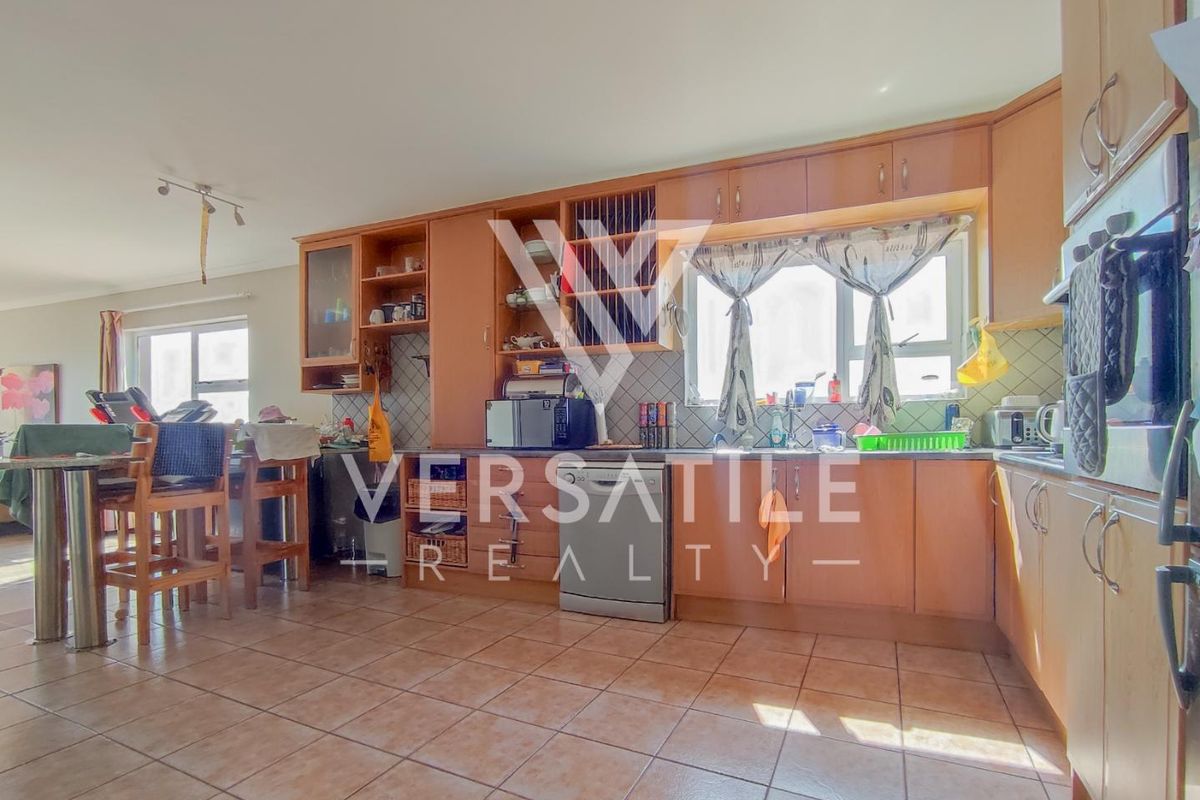 Open plan kitchen featuring laminate cabinetry, tiled flooring, and built-in appliances, offering a functional layout for cooking and dining.
