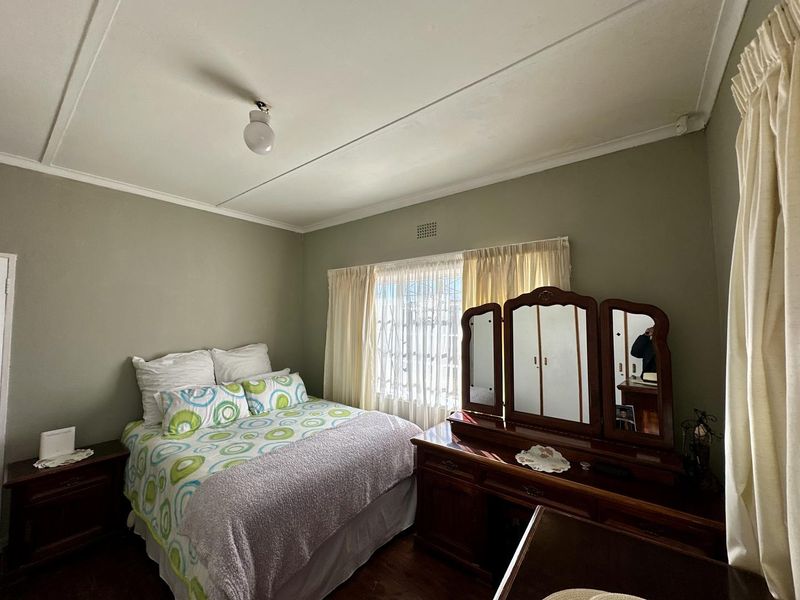 A standard bedroom featuring timber flooring and a ventilation grille, offering a neutral canvas for potential interior updates.