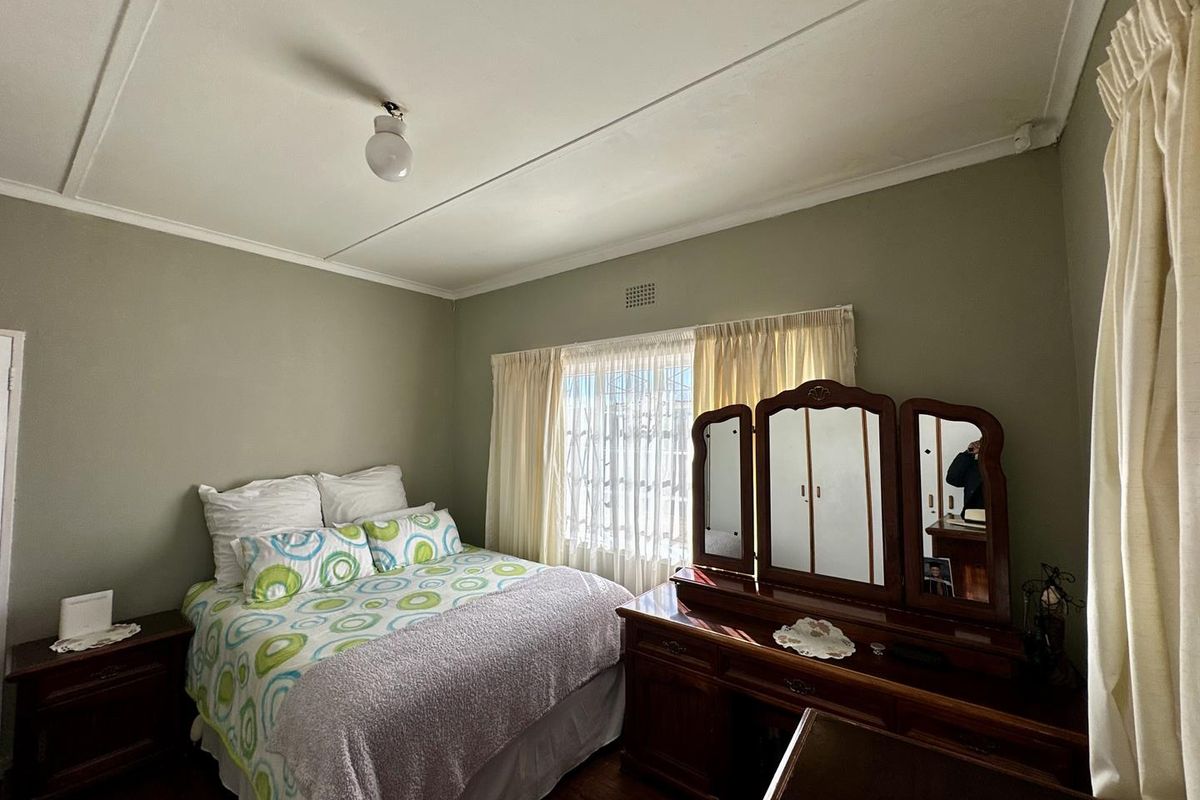 A standard bedroom featuring timber flooring and a ventilation grille, offering a neutral canvas for potential interior updates.