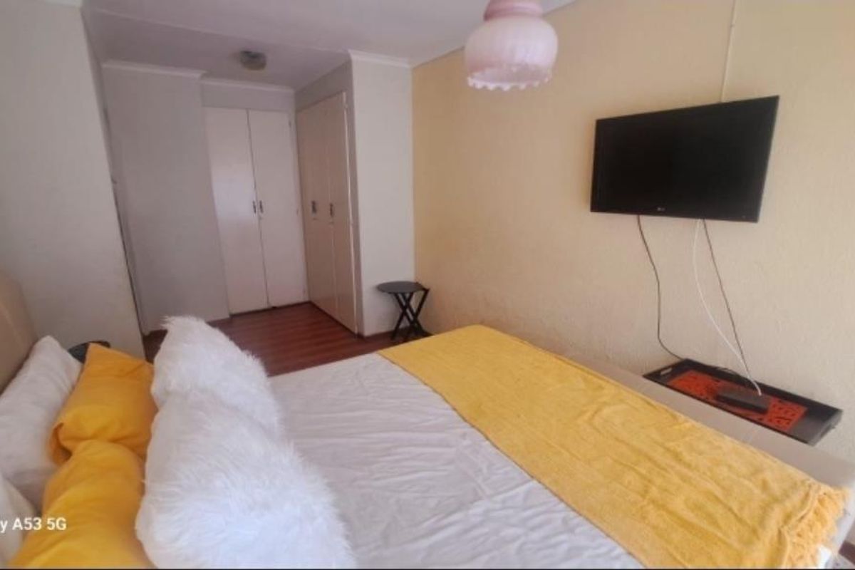 A bedroom featuring built-in cupboards and laminate flooring, providing functional storage space.