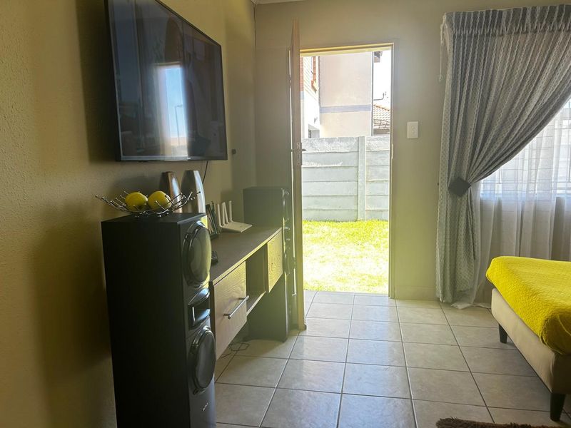 A living room area featuring tiled flooring and direct access to the rear garden through an external door.