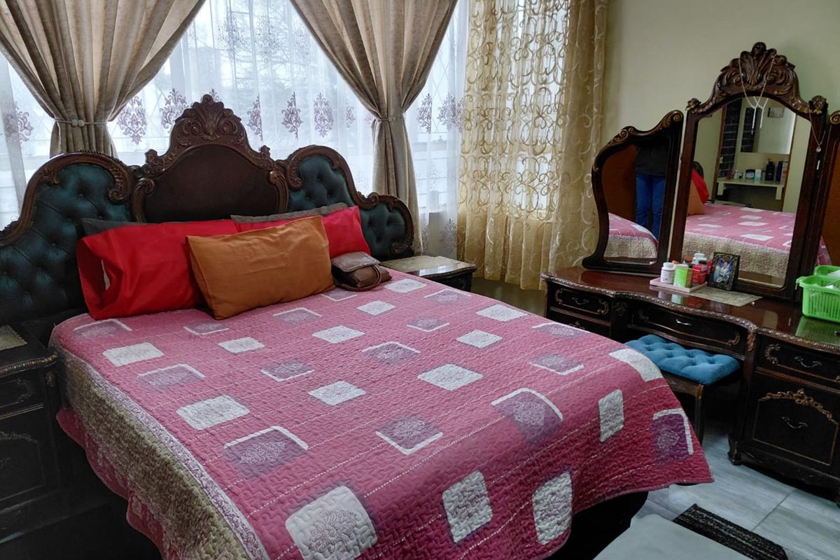 A bedroom featuring tiled flooring and a large window with curtains, providing natural light to the space.
