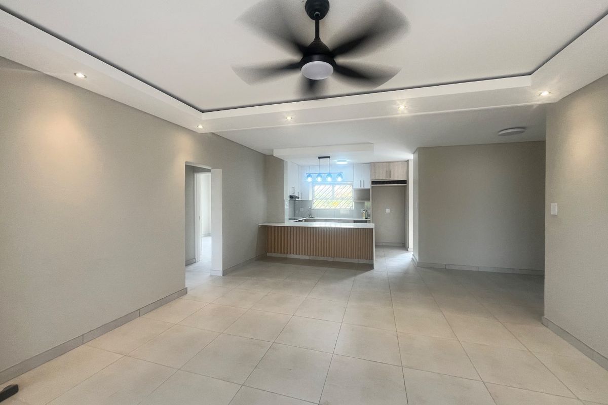 Spacious open-plan living area featuring modern tiled flooring, recessed lighting, a ceiling fan, and a contemporary kitchen with built-in cabinetry and island.