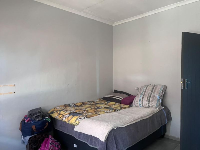 A compact bedroom featuring neutral wall finishes and a standard internal door, requiring minor cosmetic updates to improve its overall presentation.
