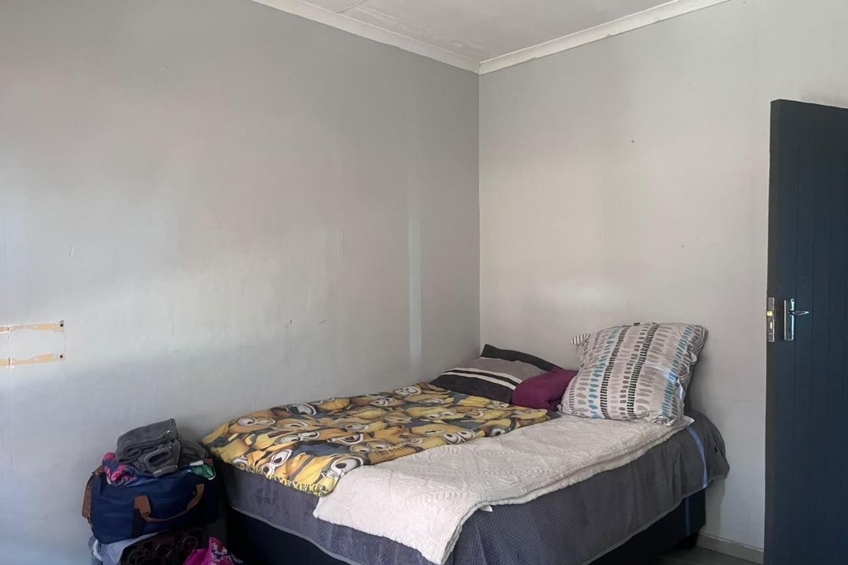 A compact bedroom featuring neutral wall finishes and a standard internal door, requiring minor cosmetic updates to improve its overall presentation.