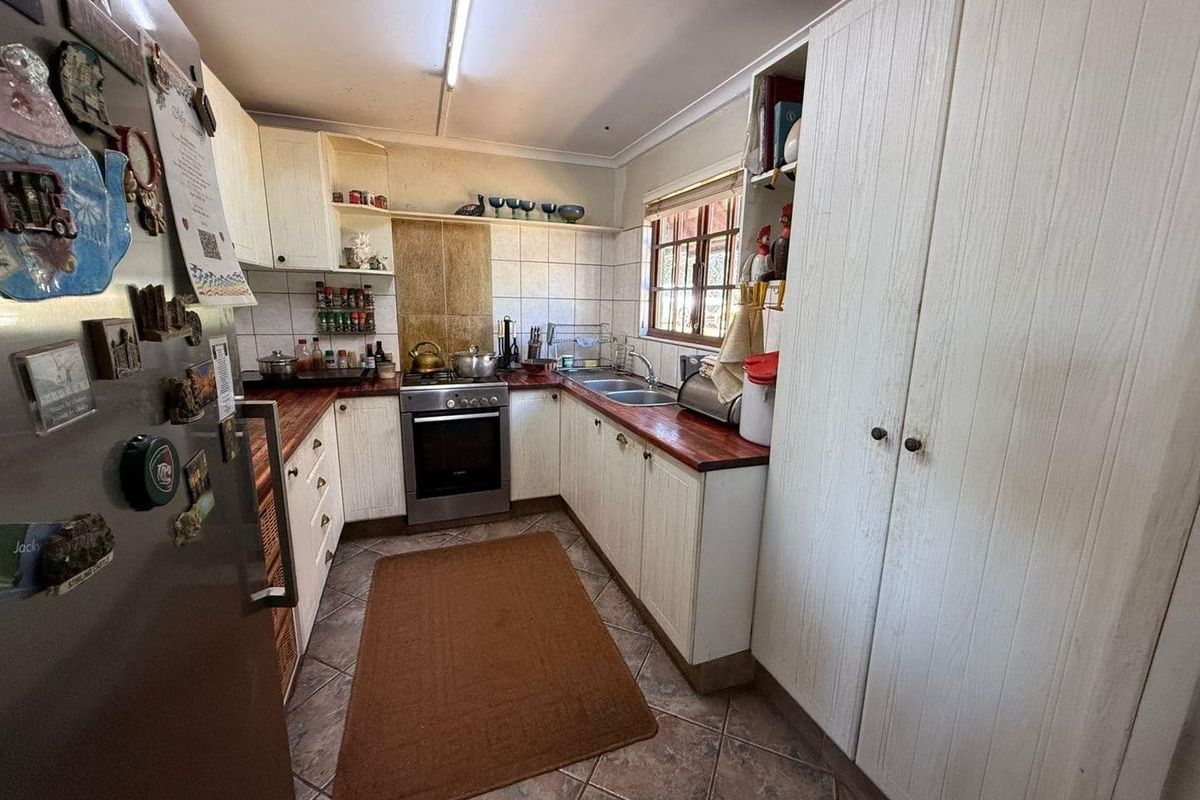 Functional kitchen featuring wooden countertops, built-in cabinetry, a stainless steel stove, and tiled flooring with a practical U-shaped layout.