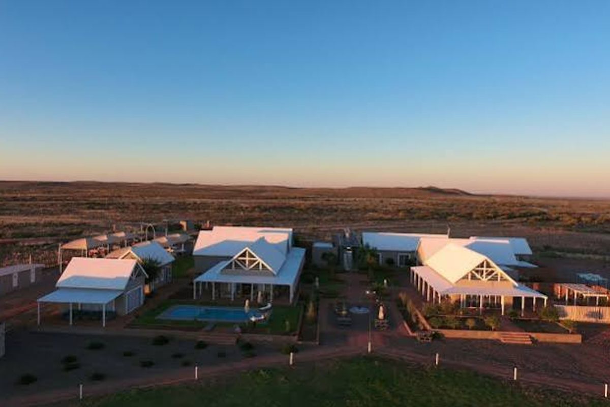 Aerial view of a farm property featuring multiple residential structures with pitched roofs, a central swimming pool, and expansive surrounding landscape.