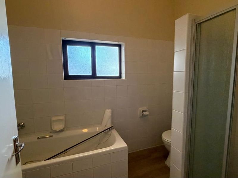 A functional bathroom featuring a built-in bathtub, separate shower enclosure, and toilet with tiled wall finishes.