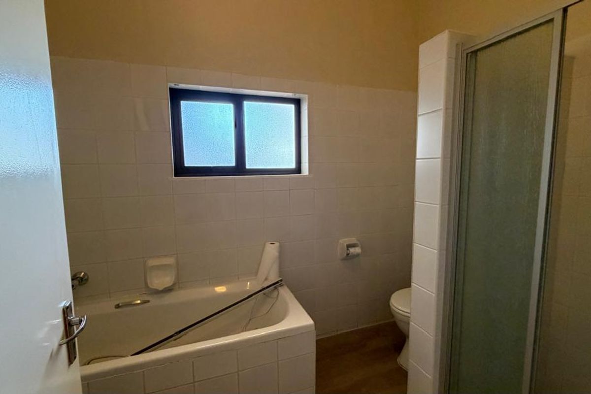 A functional bathroom featuring a built-in bathtub, separate shower enclosure, and toilet with tiled wall finishes.