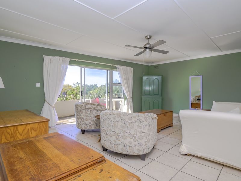 Spacious living room featuring tiled flooring, a ceiling fan, and large sliding glass doors providing access to an outdoor balcony area.