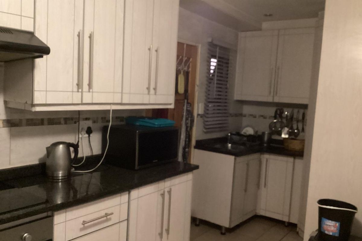 A functional kitchen featuring white cabinetry, dark countertops, a built-in oven, and an extractor fan.