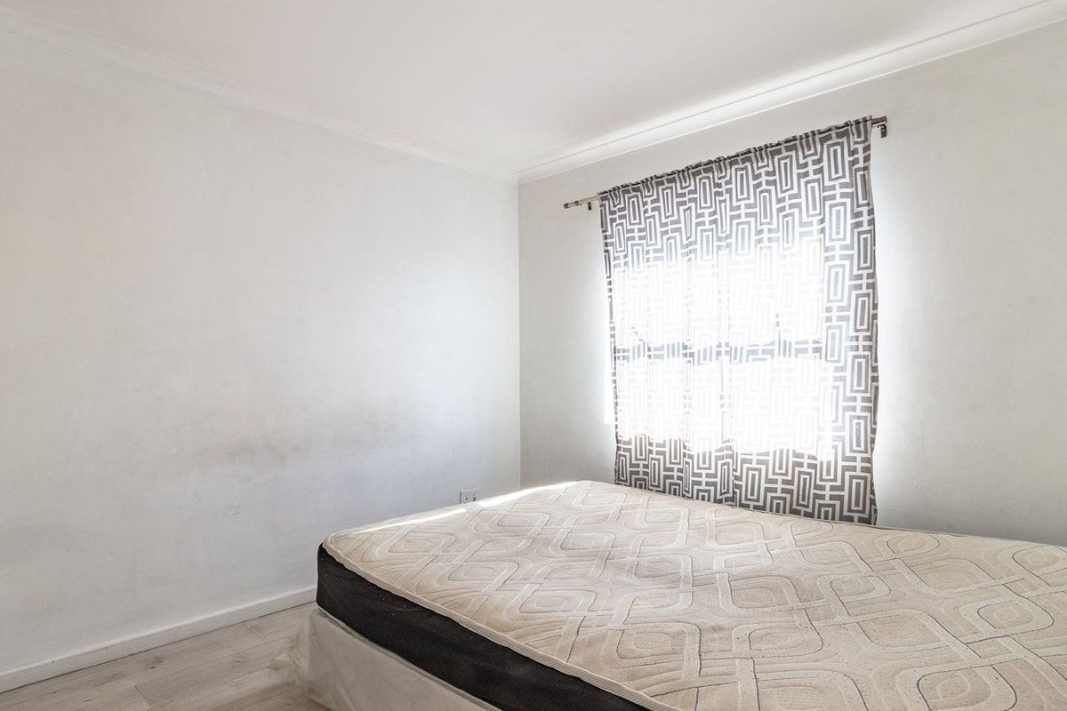 A bedroom featuring laminate flooring and coving, currently requiring cosmetic attention to the wall finishes.