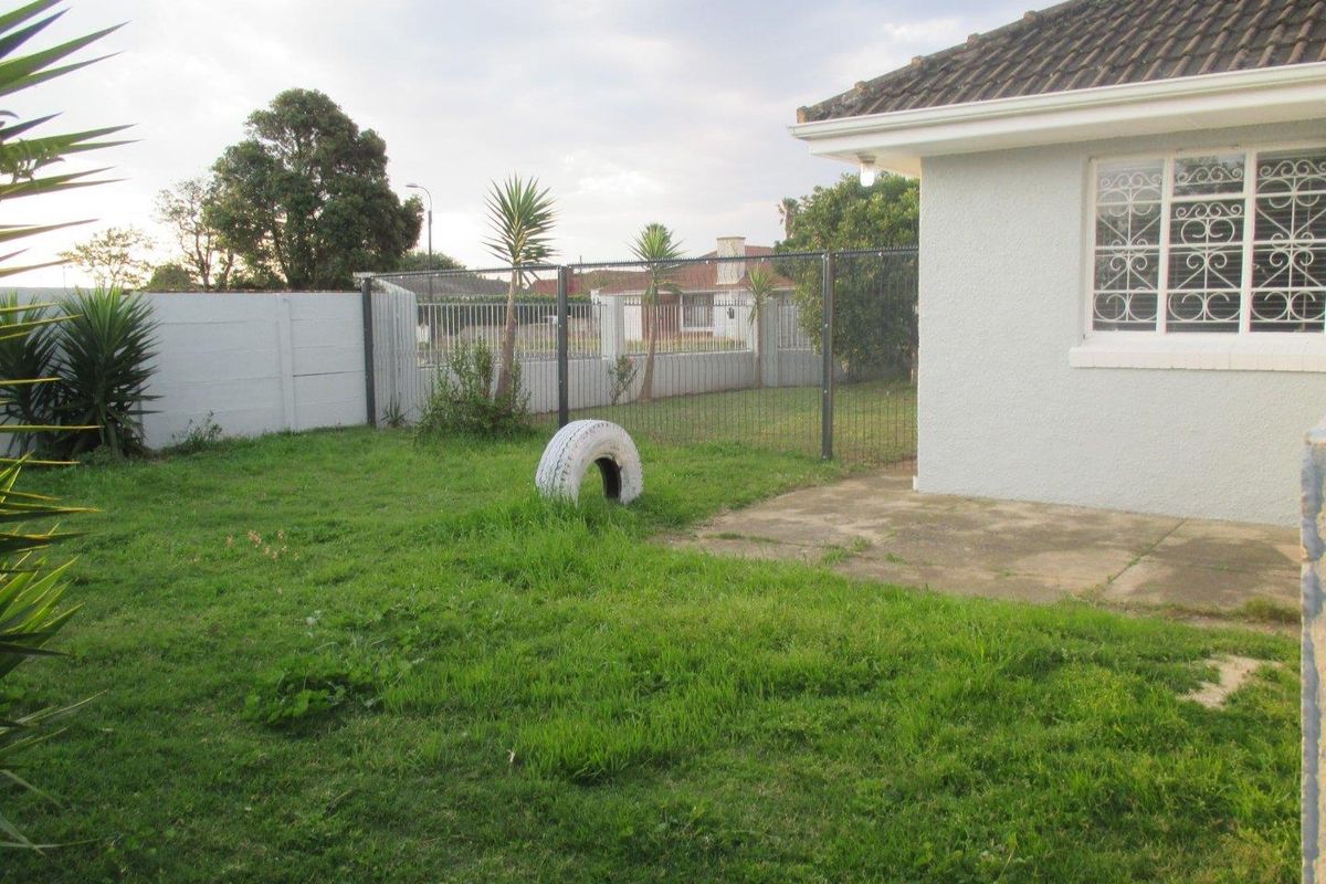 A rear garden area featuring a concrete patio, perimeter wall, and security fencing, providing a private outdoor space for the property.