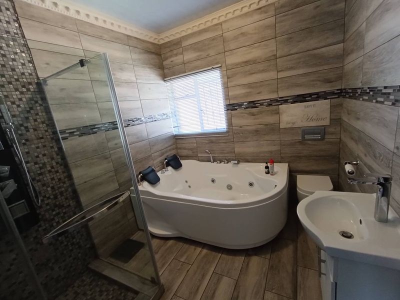 Modern bathroom featuring wood-look wall tiles, a corner jacuzzi bathtub, a separate glass shower enclosure, and a wall-mounted toilet.