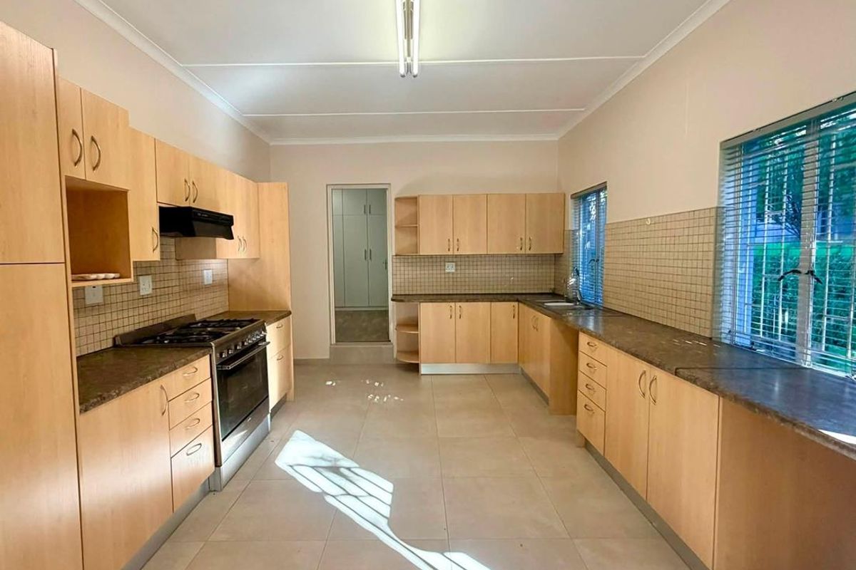 Spacious kitchen featuring light wood-finish cabinetry, laminate countertops, tiled backsplash, and built-in cooking appliances, offering a functional and well-lit workspace.