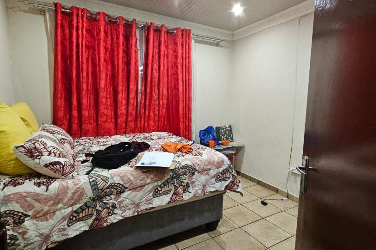 A bedroom featuring tiled flooring, recessed ceiling lighting, and a standard door entrance.