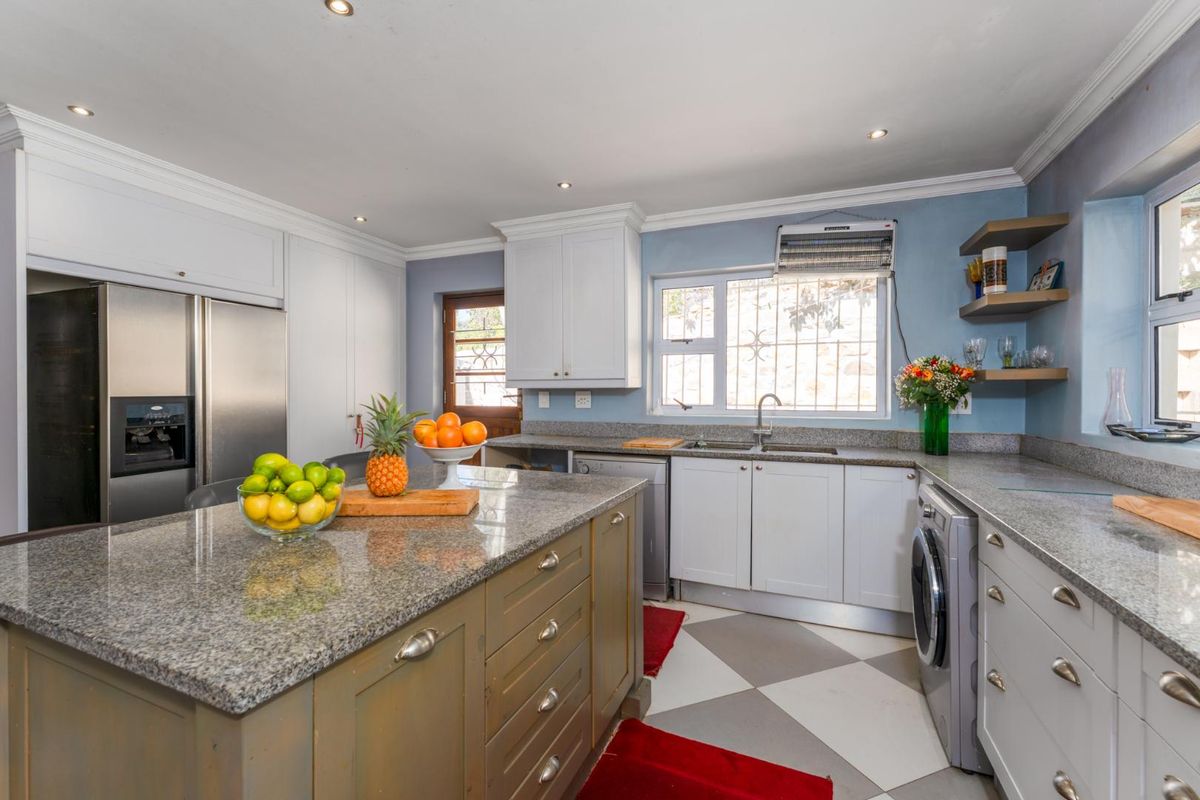 A functional kitchen featuring granite countertops, a central island, built-in cabinetry, and a tiled floor with a classic checkerboard pattern.