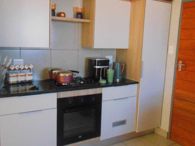 A functional kitchen featuring built-in cabinetry, a gas hob, an integrated oven, stone countertops, and tiled flooring.