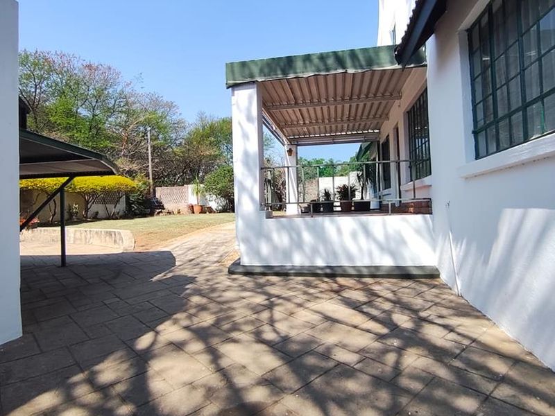 A rear exterior view featuring a paved courtyard and a covered patio area attached to the main house structure.