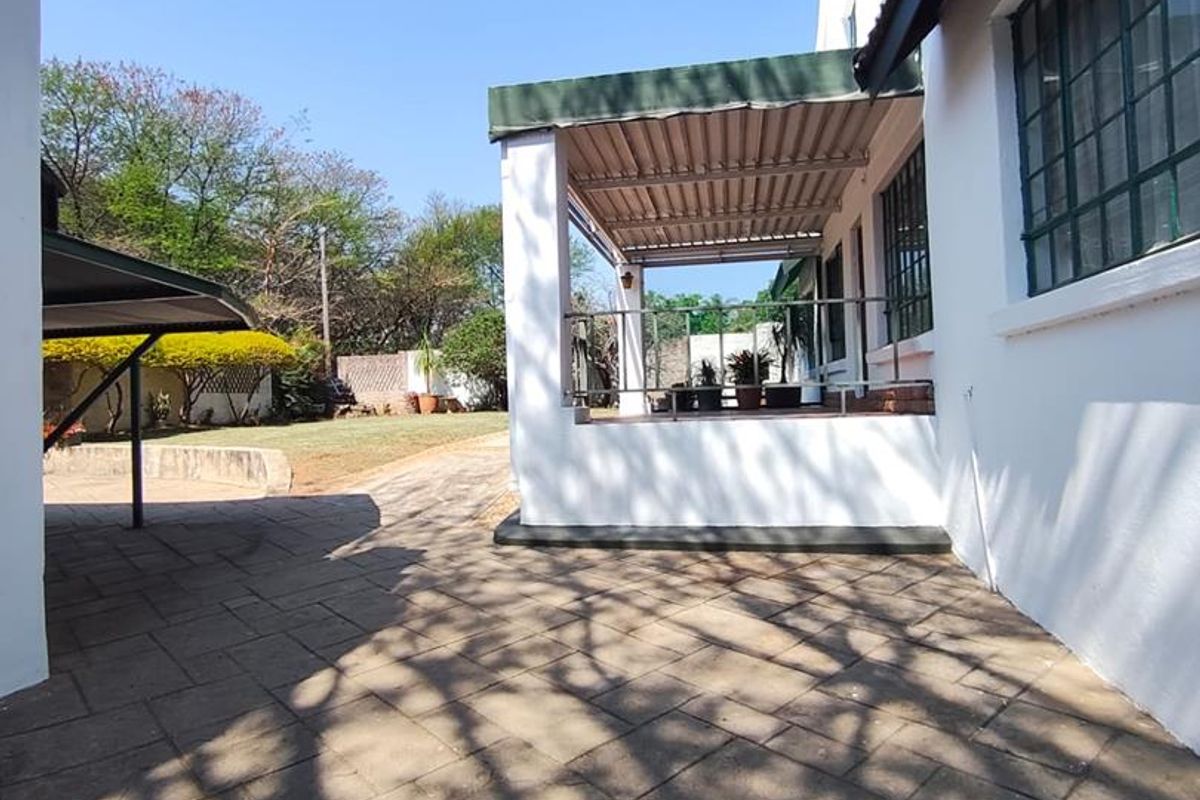 A rear exterior view featuring a paved courtyard and a covered patio area attached to the main house structure.