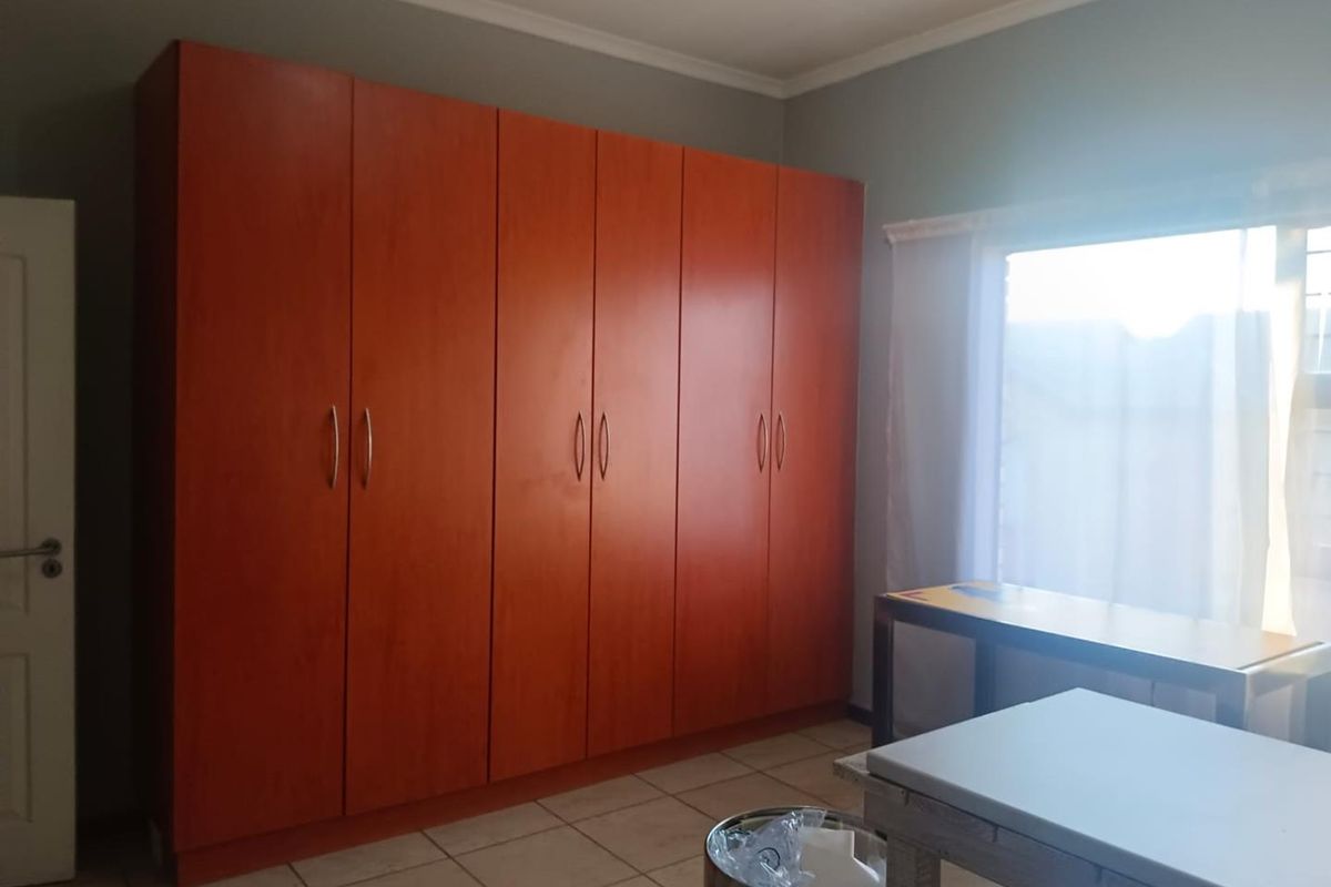 A bedroom featuring extensive built-in wooden cupboards and tiled flooring, offering ample storage space.