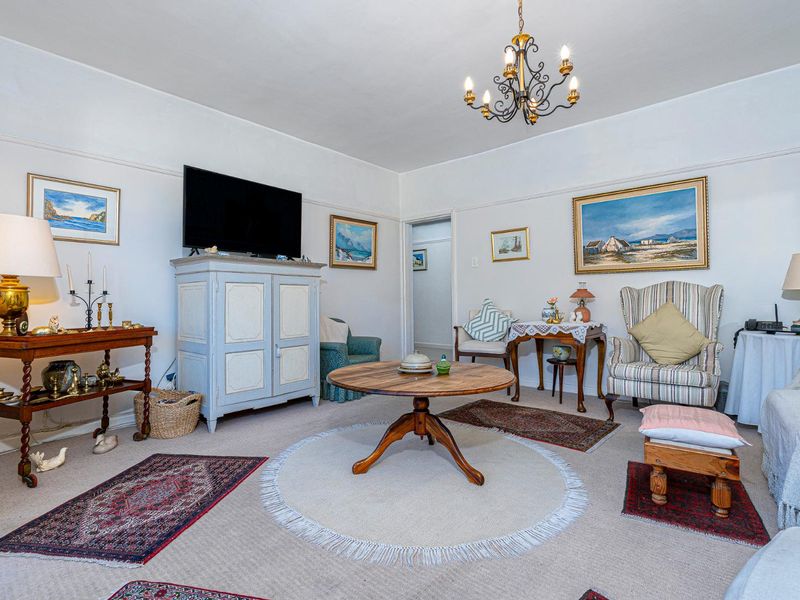 A traditional living room featuring classic picture rails and a central chandelier, offering a comfortable and well-maintained living space.
