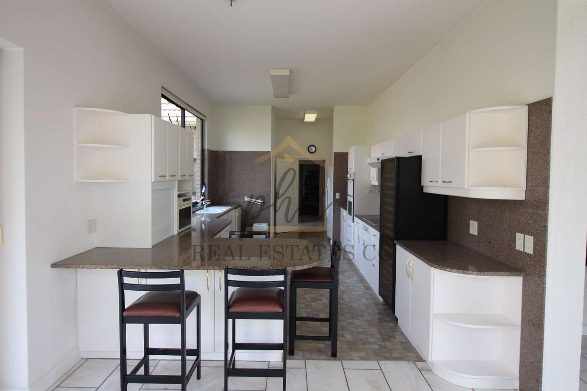 A functional kitchen featuring white cabinetry, granite countertops, a breakfast bar, and integrated appliances, offering a practical layout for daily meal preparation.