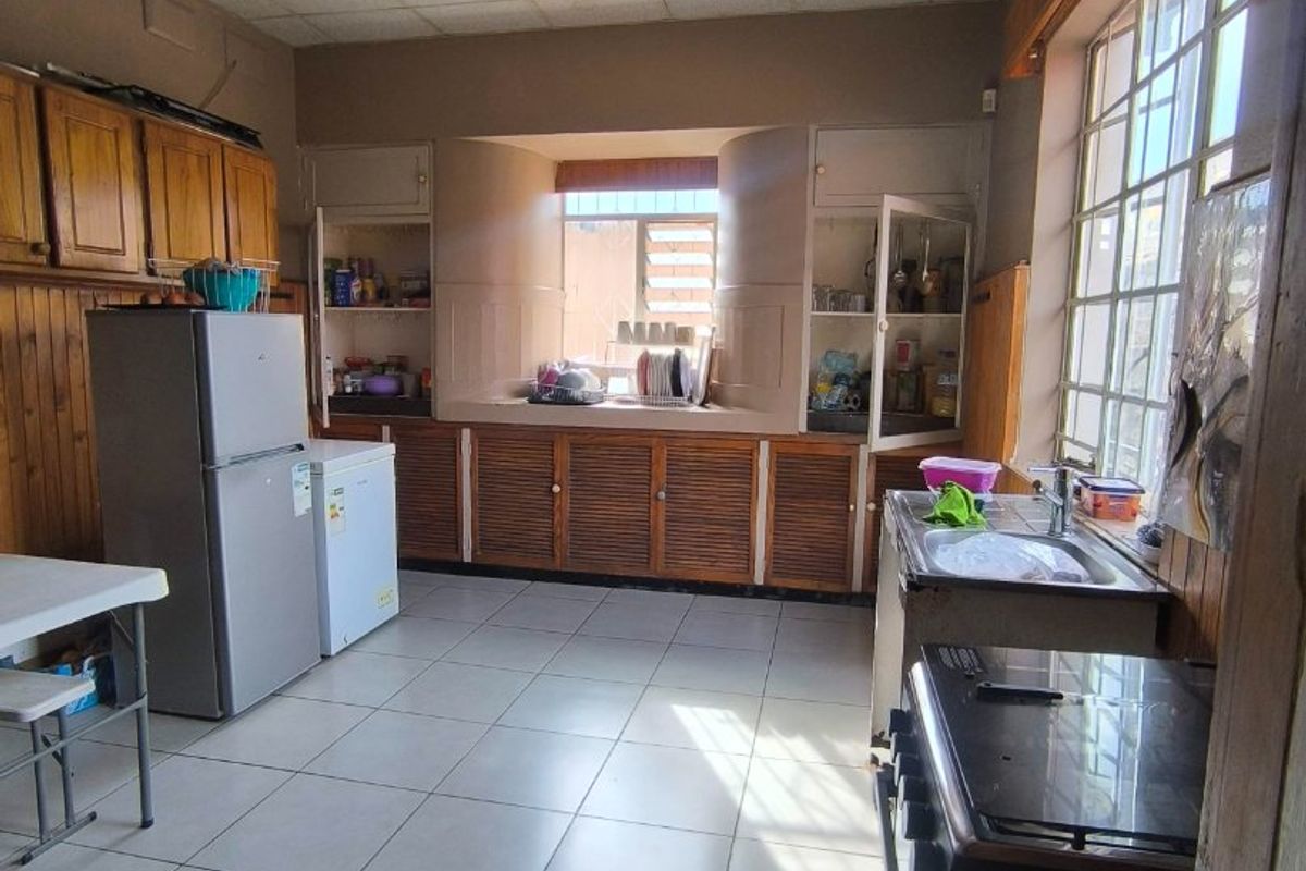 A dated kitchen featuring wooden cabinetry, tiled flooring, and a drop ceiling, offering significant potential for modernization and renovation.