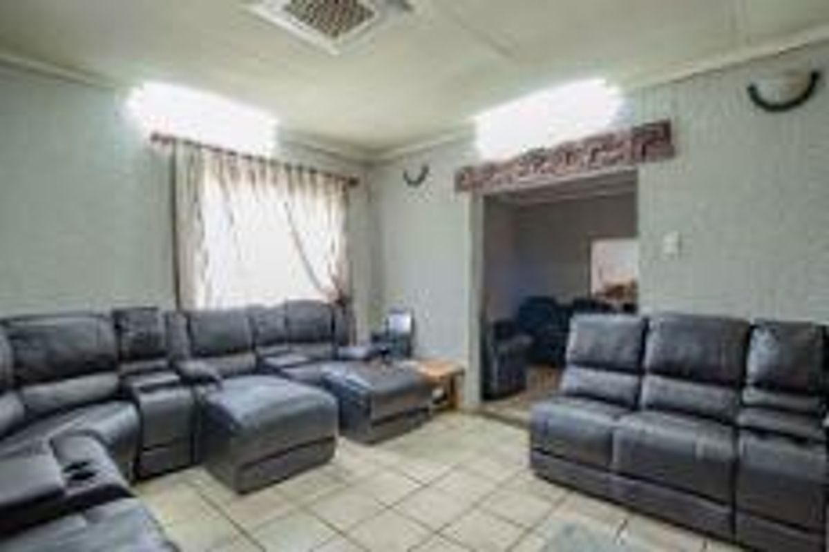 A spacious living room featuring tiled flooring, neutral wall finishes, and a wide doorway leading to an adjacent room.