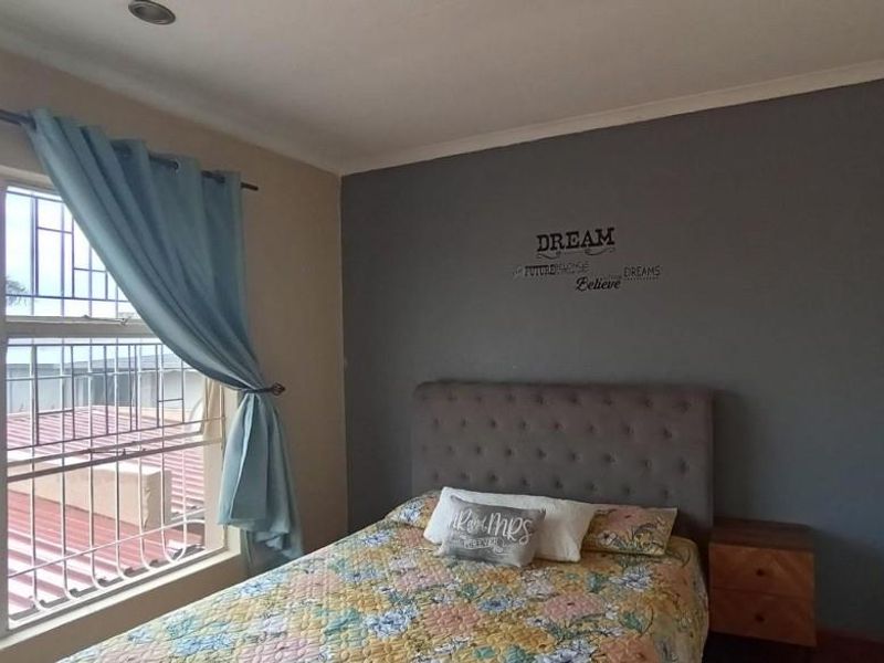 A bedroom featuring built-in cupboards, security bars on the window, and recessed downlighting.