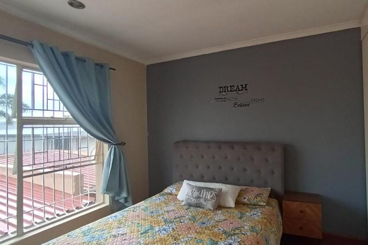 A bedroom featuring built-in cupboards, security bars on the window, and recessed downlighting.