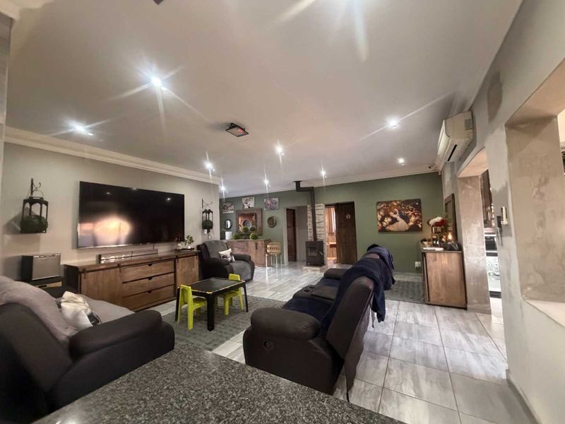 Spacious living room featuring tiled flooring, a wood-burning fireplace, and recessed lighting, with some areas requiring final wall finishing.