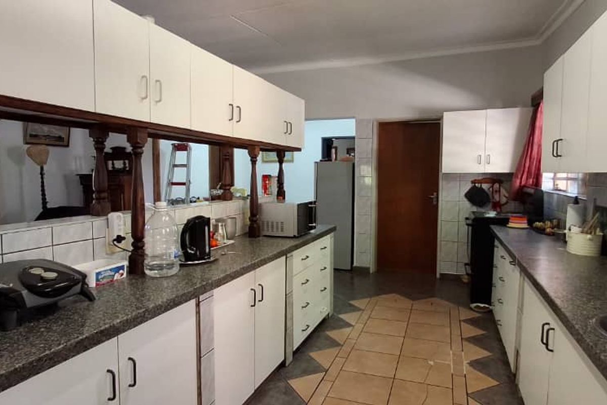 A functional kitchen featuring white cabinetry, stone-look countertops, tiled backsplash, and tiled flooring, offering a practical layout for daily meal preparation.