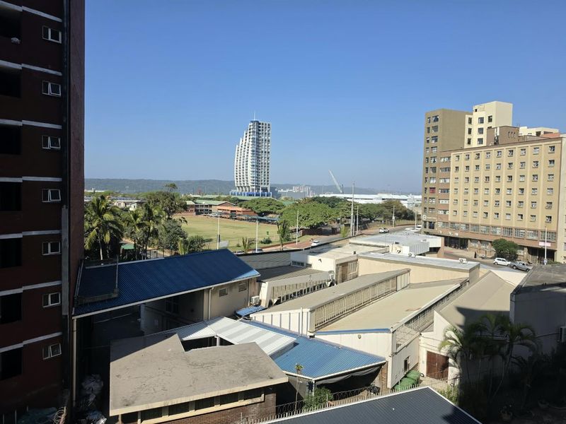 An elevated urban view overlooking surrounding commercial buildings, industrial rooftops, and distant city skyline.