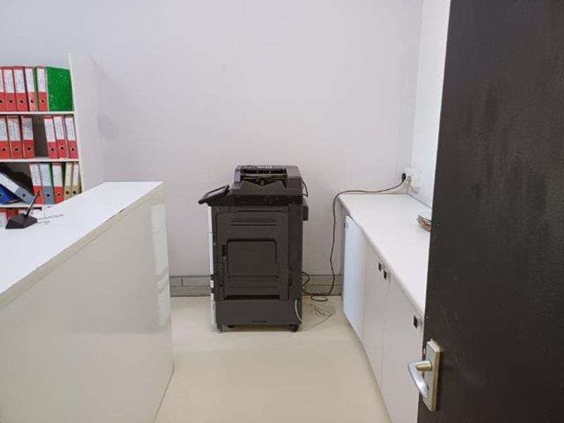 A functional office space featuring built-in white cabinetry and ample storage, suitable for a professional work environment.
