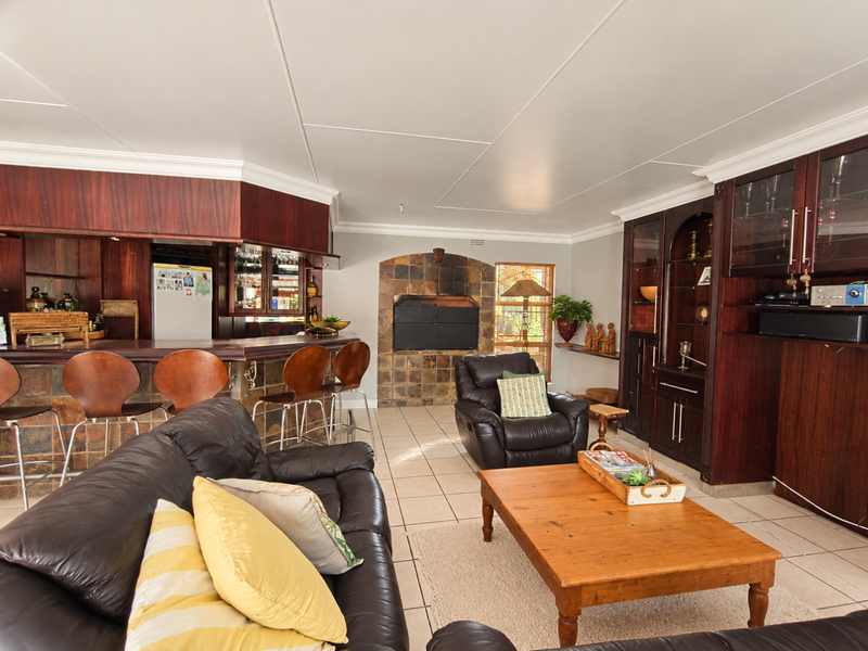 Open-plan living area featuring a built-in bar, stone-clad fireplace, and extensive dark wood cabinetry, offering a functional space with traditional design elements.