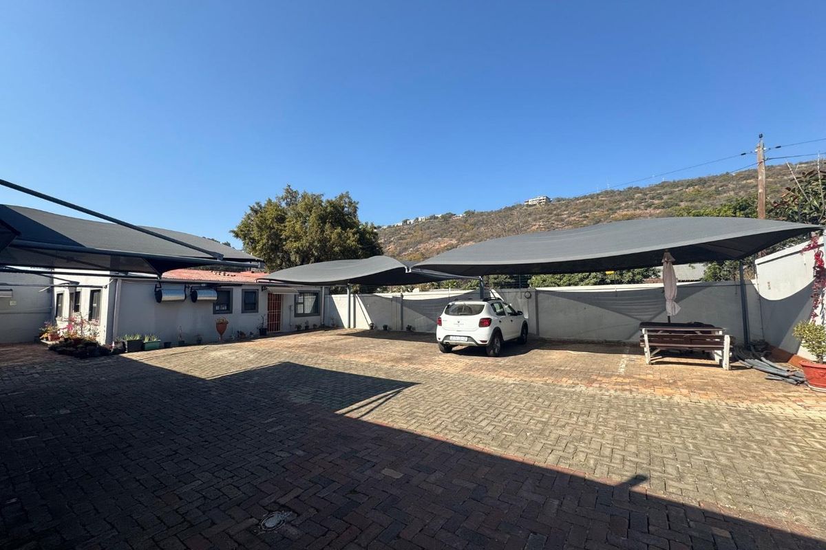 Spacious paved rear courtyard featuring multiple shade cloth carports and secure boundary walling, providing ample off-street parking space.