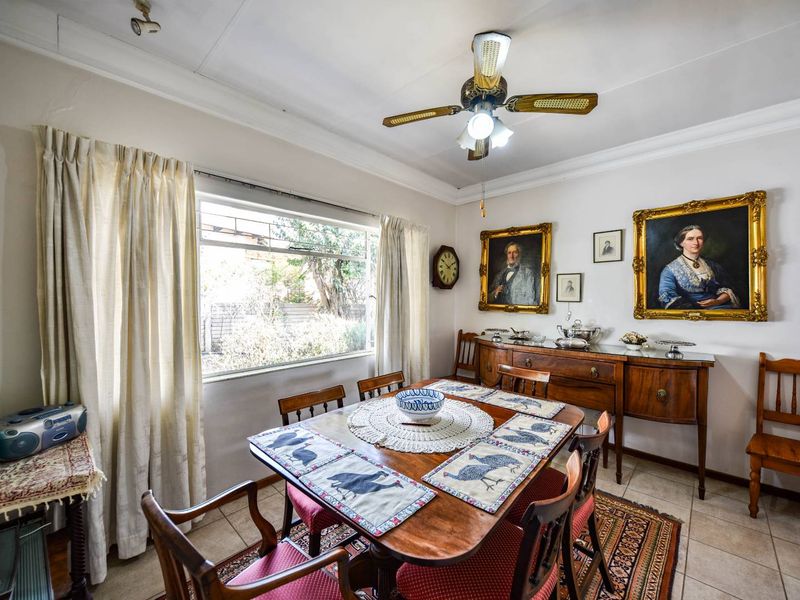 A well-lit dining room featuring tiled flooring, a ceiling fan, and a large window providing natural light.