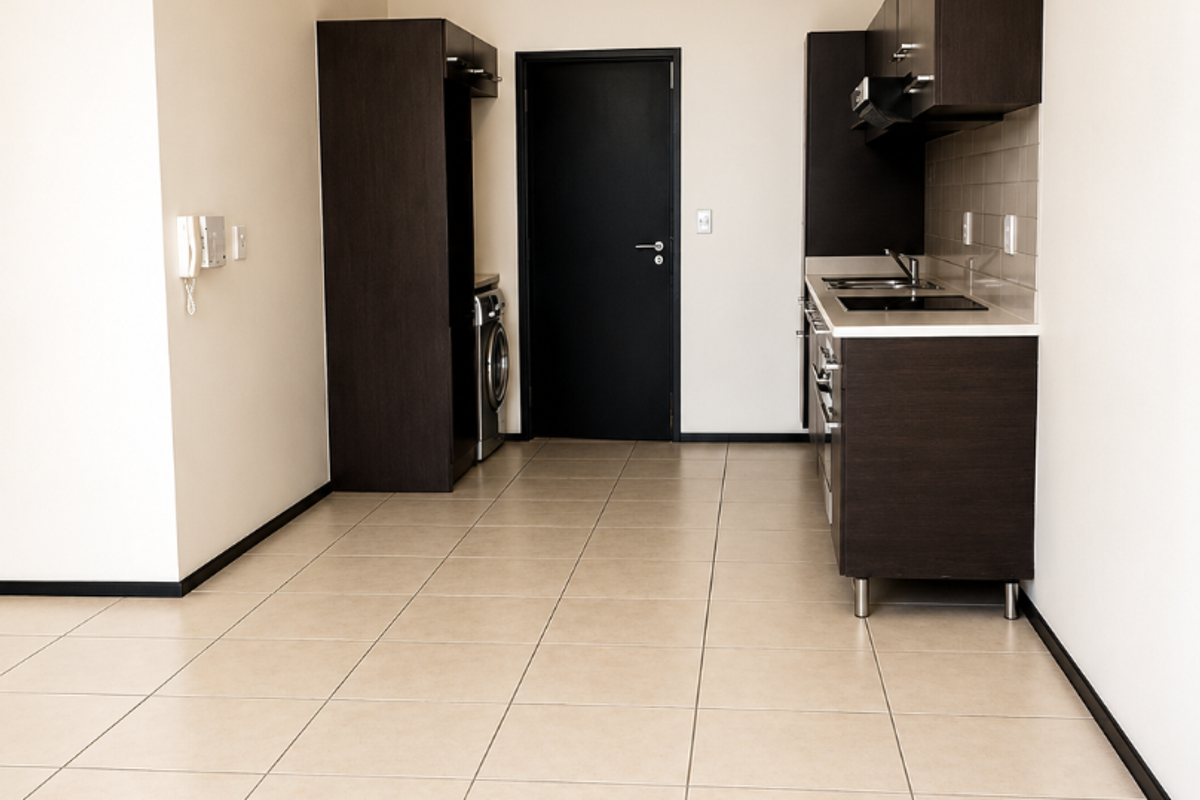 A clean, modern kitchen featuring dark wood cabinetry, integrated appliances, and neutral tiled flooring in an open-plan layout.