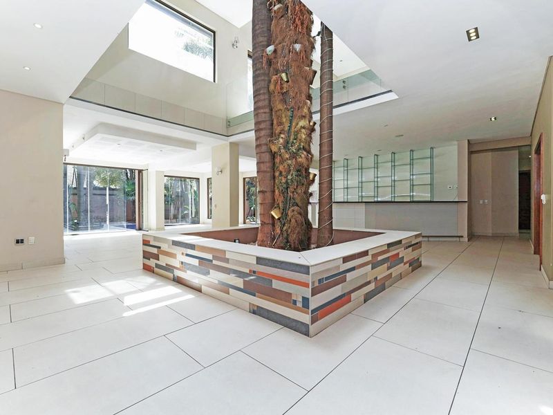 Spacious open-plan living area featuring a unique central atrium with a skylight, tiled flooring, and a built-in bar area.