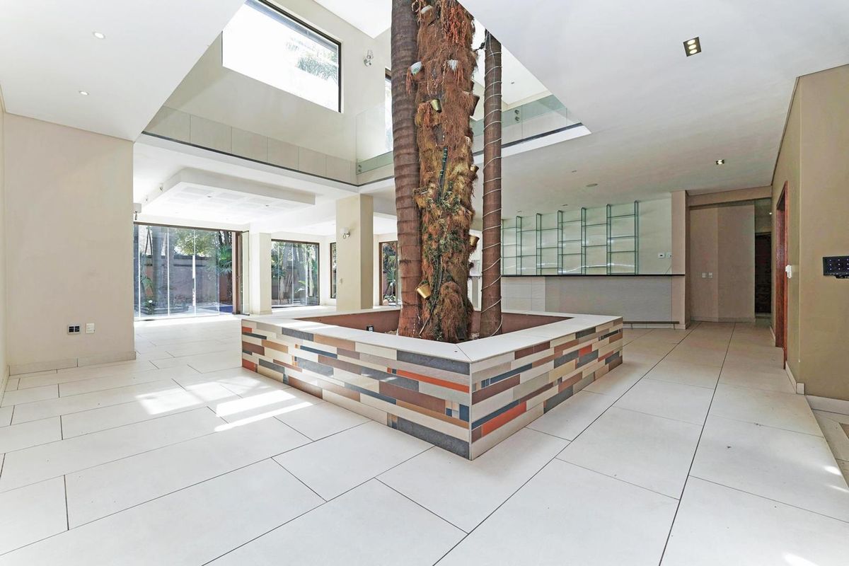 Spacious open-plan living area featuring a unique central atrium with a skylight, tiled flooring, and a built-in bar area.
