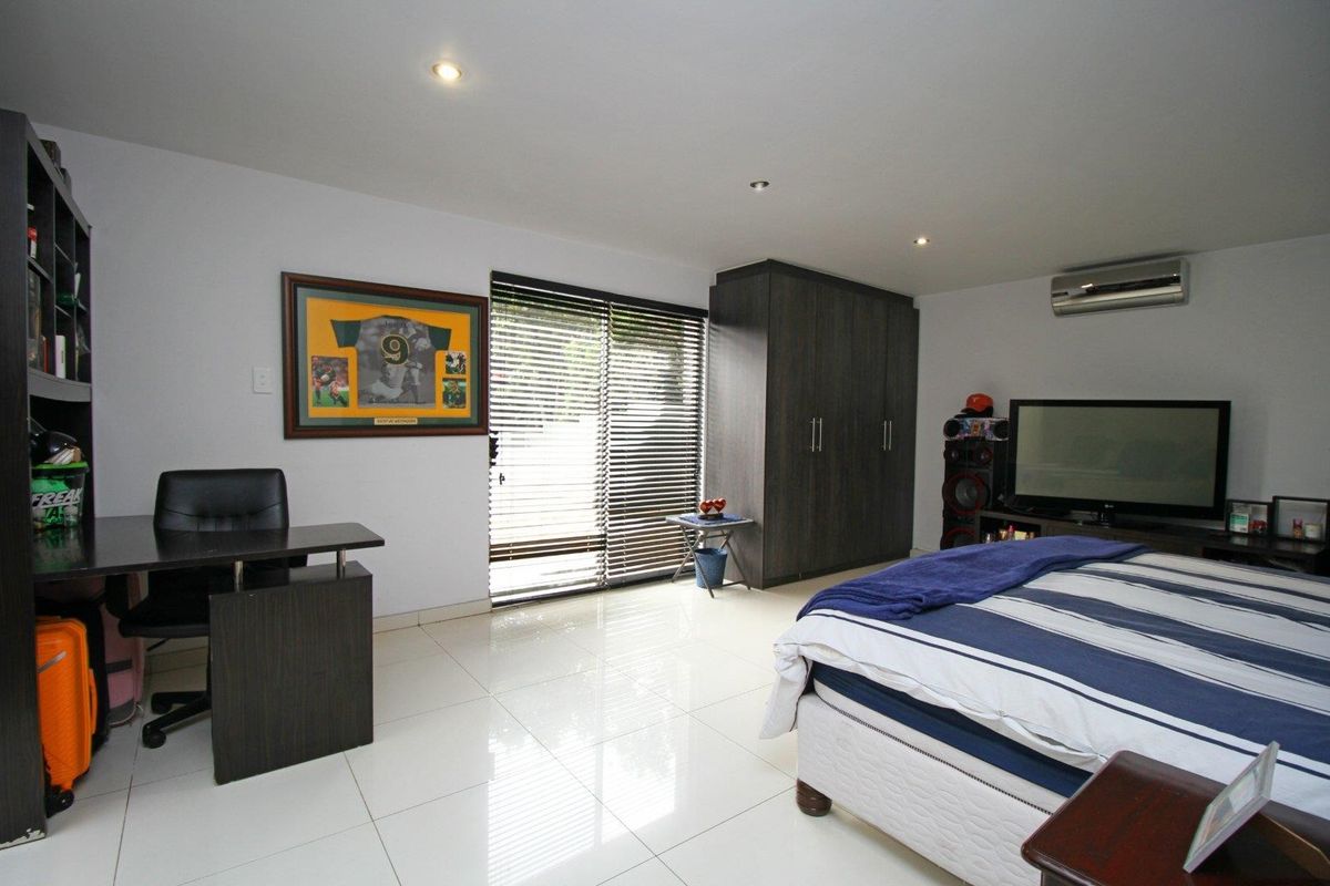 Spacious bedroom featuring tiled flooring, built-in cupboards, recessed lighting, and a wall-mounted air conditioning unit.