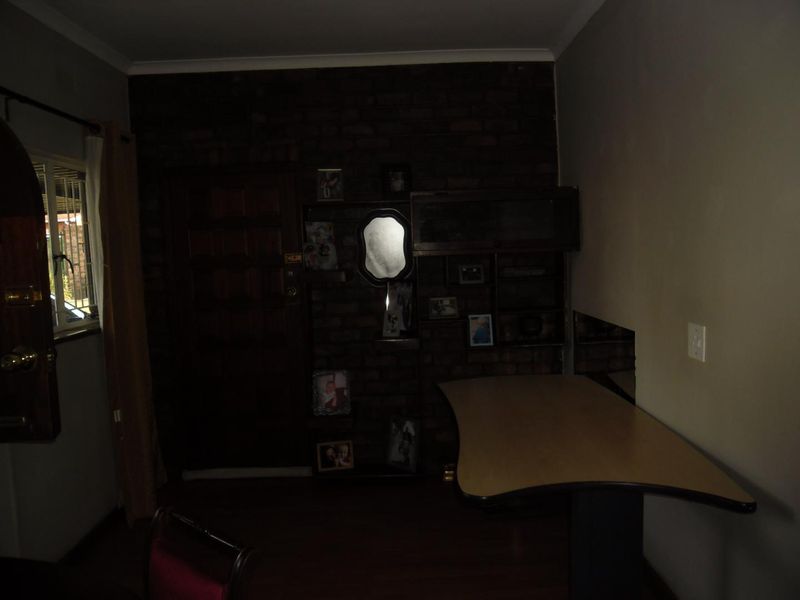 A dimly lit living area featuring an exposed brick wall with integrated shelving and a timber entrance door.