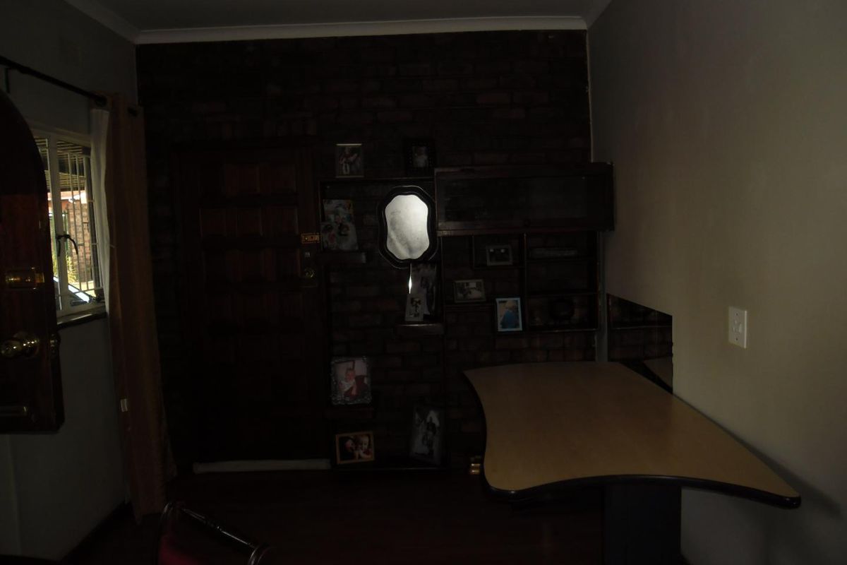 A dimly lit living area featuring an exposed brick wall with integrated shelving and a timber entrance door.