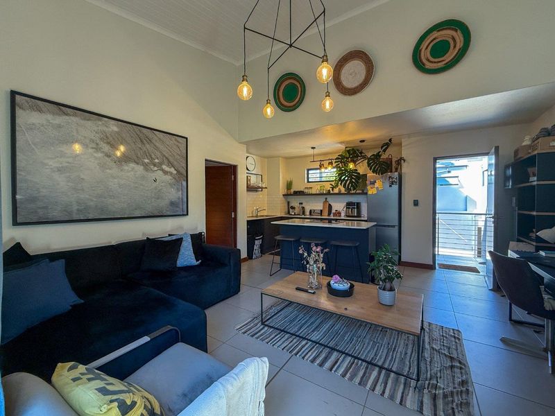 Open-plan living area featuring a modern kitchen with a central island, vaulted ceilings, and tiled flooring, seamlessly connecting to the main living space.