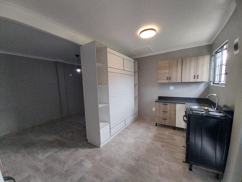 Open plan kitchen and living area featuring modern cabinetry, tiled flooring, and a functional layout with built-in storage units.