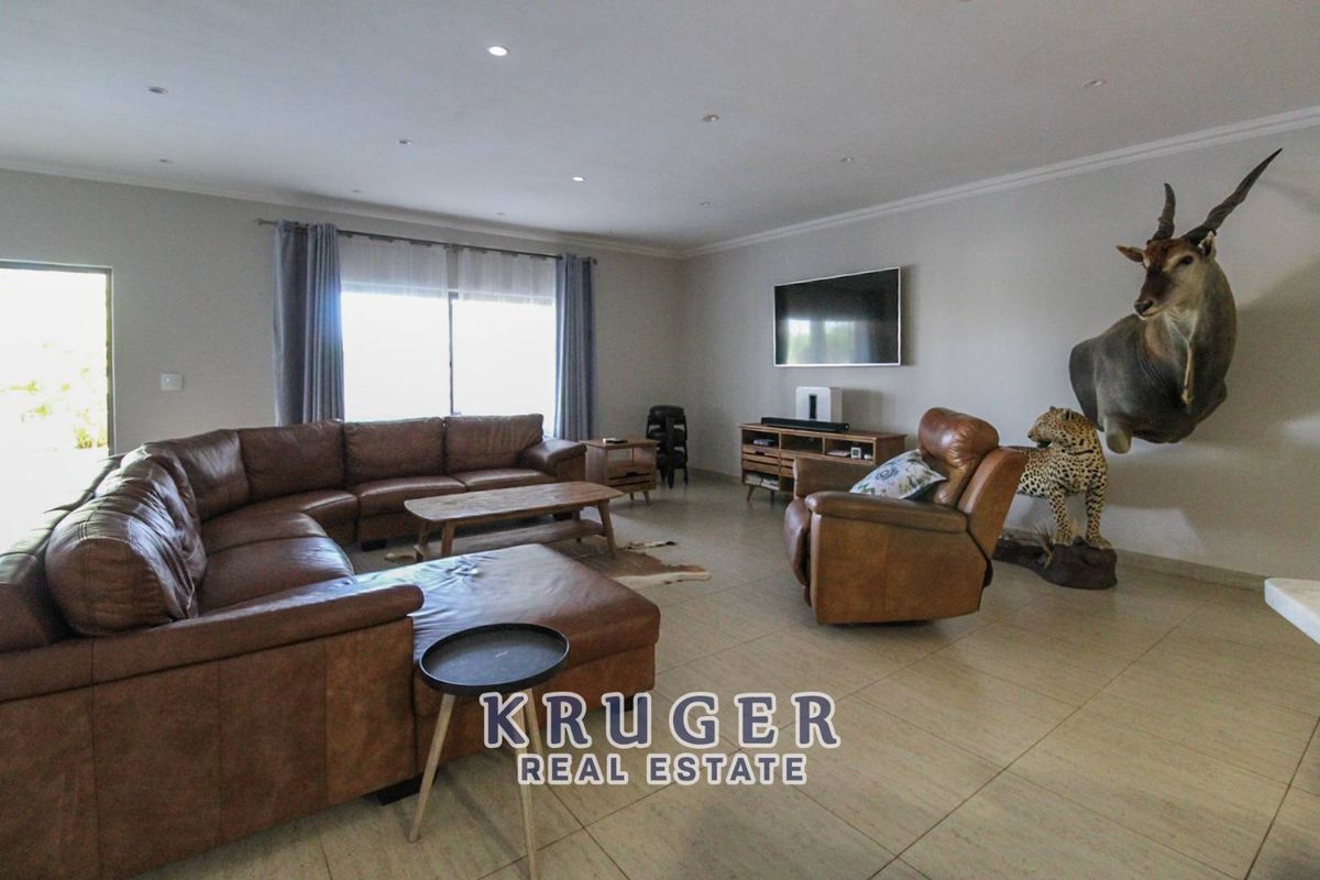 Spacious living room featuring large format floor tiles, recessed downlighting, and a sliding glass door providing natural light.